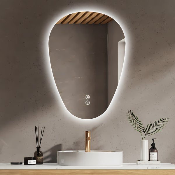 Organisch geformter Badezimmerspiegel mit LED Beleuchtung und Touch Steuerung über einem Waschbecken mit goldener Armatur im modernen Badezimmer.