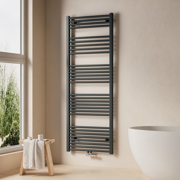 Handtuchwärmer im Badezimmer neben einer Badewanne und einem Hocker