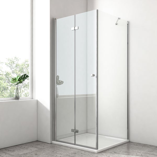 Moderne Duschkabine mit transparenten Glaswänden und Falttür, verchromten Profilen und weißer Duschwanne in einem hellen Badezimmer.