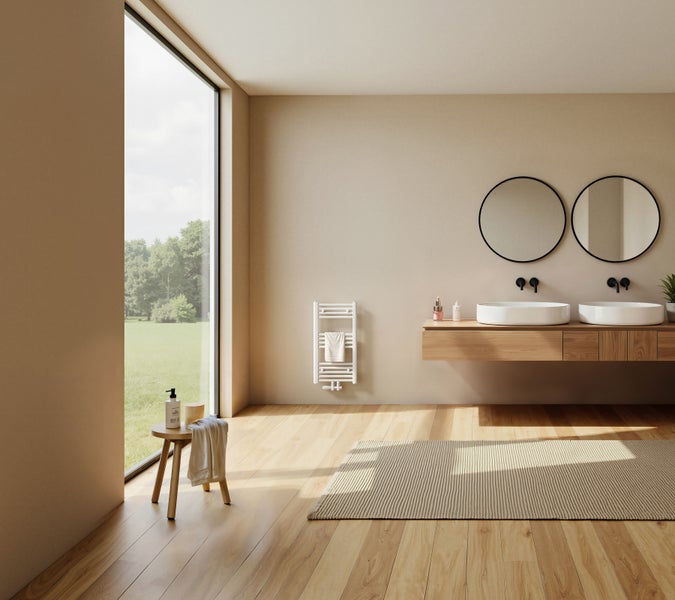 Modernes Badezimmer mit Doppelwaschtisch aus Holz, zwei runden Spiegeln, wandhängendem Handtuchheizkörper und großem Fenster mit Blick ins Grüne.