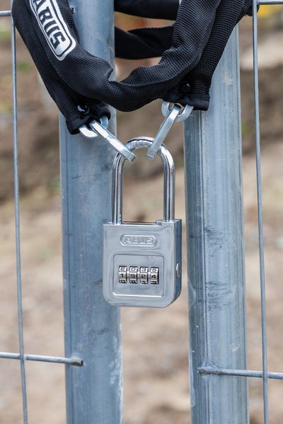 ABUS Zahlenschloss mit vierstelligem Code und Kette mit ABUS Logo an einem Metallzaun.
