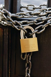 ABUS Messing-Vorhängeschloss sichert eine Metallkette an einem Tor.