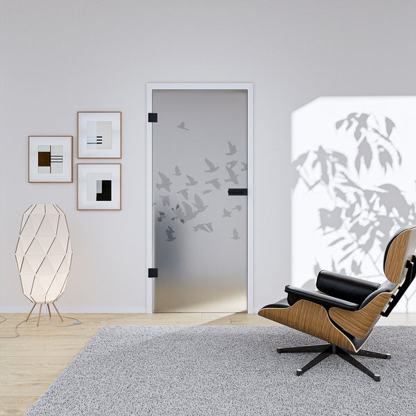 Moderne Ganzglastür mit Vogelmotiven in einem hellen Wohnzimmer mit Designer-Sessel, Stehleuchte und Teppich.