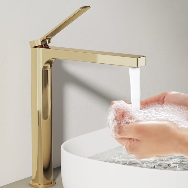 Goldene Waschtischarmatur mit laufendem Wasser und Händen