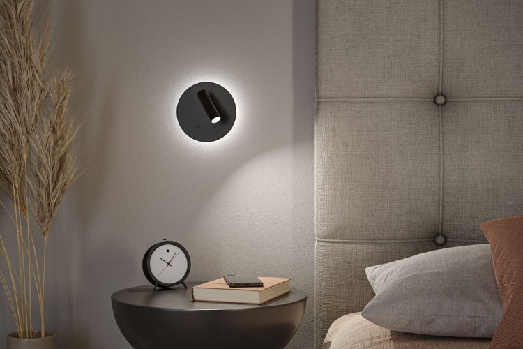 Schlafzimmer mit Nachttischlampe, Uhr und Buch