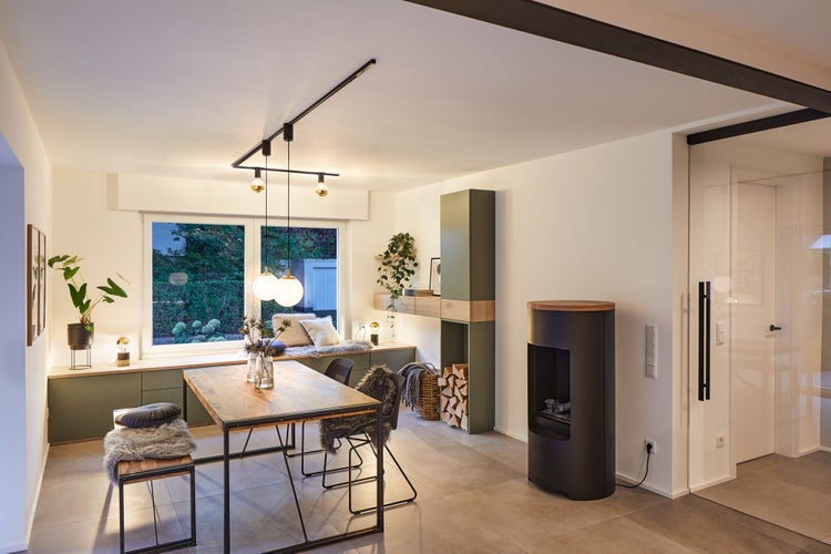 Heller Wohnraum mit Esstisch, Sitzbank am Fenster und Kaminofen