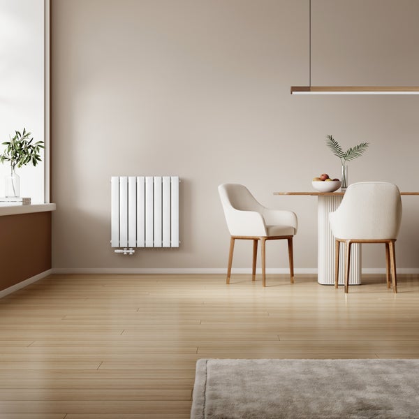 Moderner Designheizkörper montiert an einer Wand in einem hellen Esszimmer mit Holztisch, Stühlen und Holzboden.