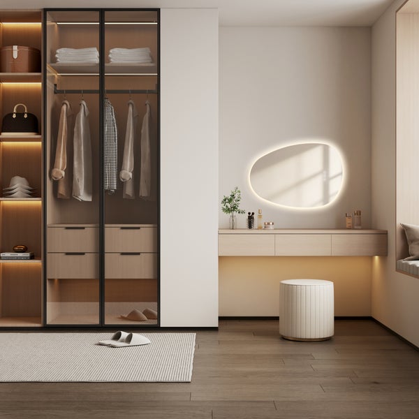 Moderne Ankleide mit beleuchtetem Kleiderschrank, wandmontiertem Schminktisch und organisch geformtem LED Spiegel in einem hellen Raum.