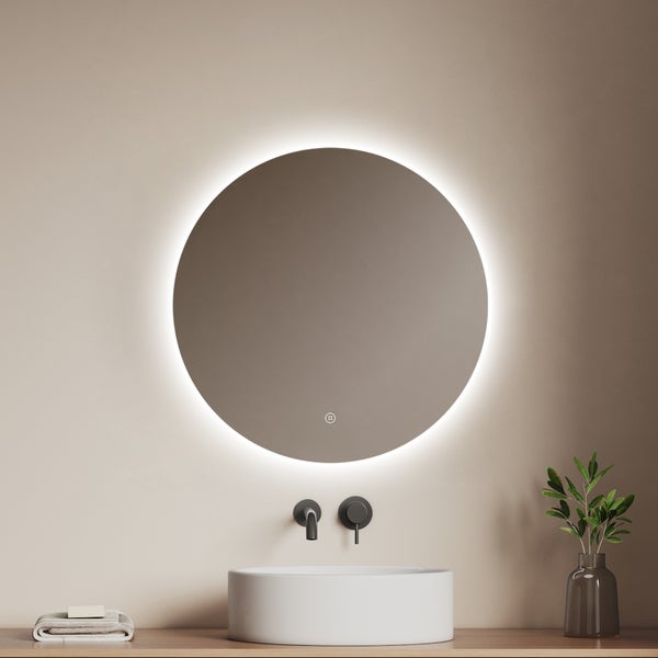 Runder Badspiegel mit LED-Beleuchtung über einem weißen Aufsatzwaschbecken und einer schwarzen Wandarmatur in modernem Design.