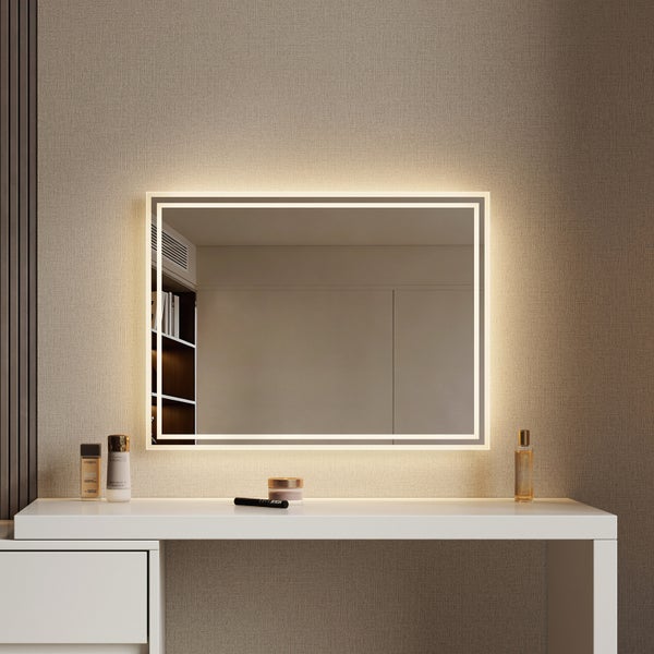 Rechteckiger Badezimmerspiegel mit integrierter LED Beleuchtung montiert an einer Wand über einem Frisiertisch mit Kosmetikartikeln.