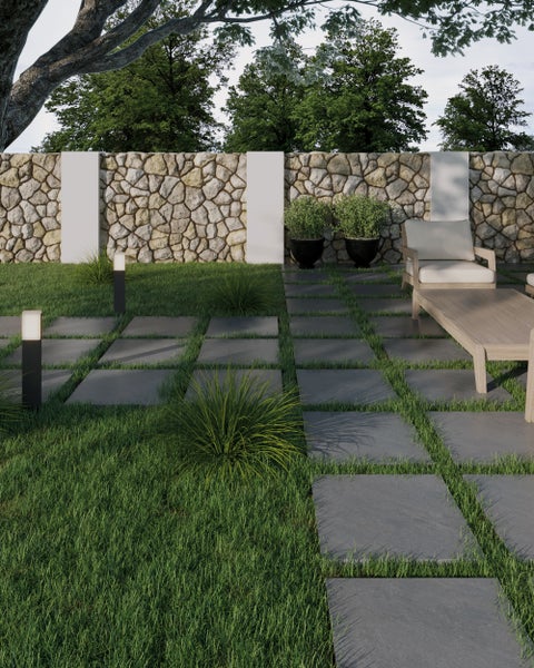 Moderner Garten mit Schieferplatten im Rasen, Gartenbeleuchtung, Gartenmöbeln aus Holz und einer Natursteinmauer.