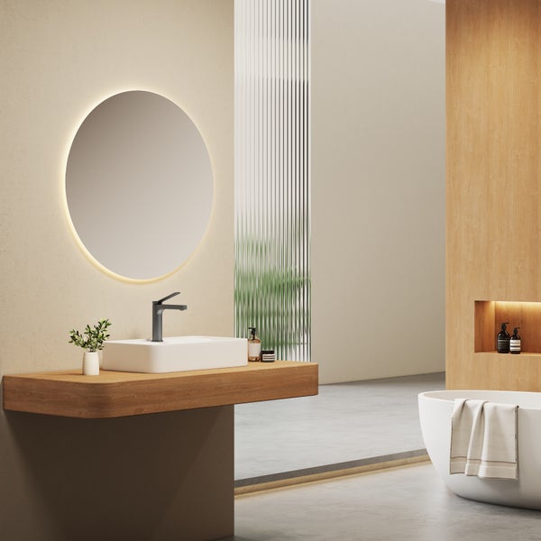 Modernes Badezimmer mit Waschtisch aus Holz, Aufsatzwaschbecken, runder LED Spiegel und freistehender Badewanne in einem minimalistischen Design.