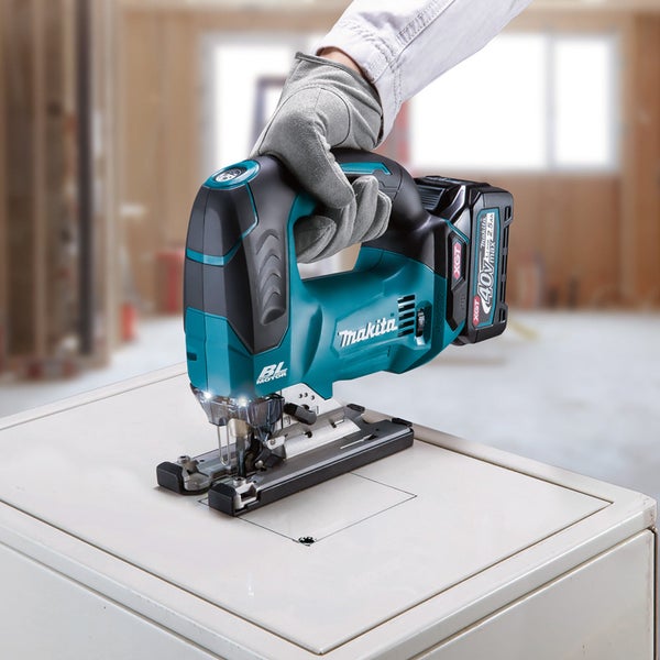 Eine Person verwendet eine Makita Akku Pendelhubstichsäge 40 Volt mit bürstenlosem Motor für einen präzisen Schnitt in eine Platte.
