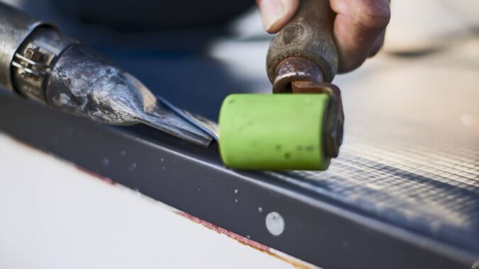 Handwerker bearbeitet Material mit Schweißgerät und Andrückrolle.