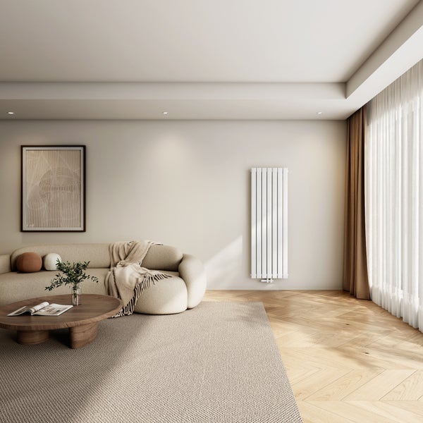 Moderner vertikaler Designheizkörper in einem hellen Wohnzimmer mit Sofa, Holztisch und Fischgrätparkett