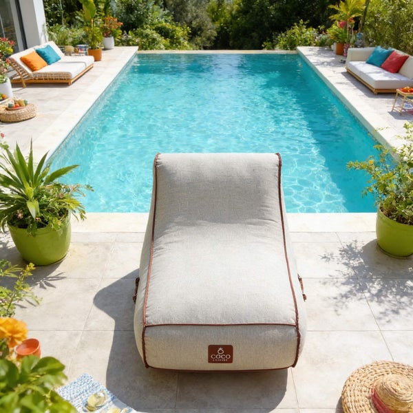Outdoor-Sitzsack vor einem Swimmingpool in einem hellen Garten mit Pflanzen und Gartenmöbeln.