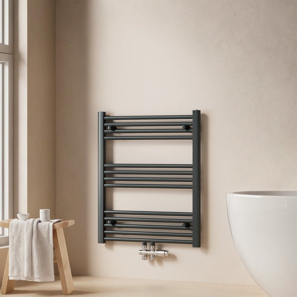 Wandmontierter Handtuchwärmer aus Metall im Badezimmer neben Fenster und Badewanne.