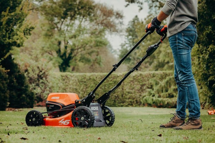 Person bedient einen Rasenmäher der Marke Echo im Garten.