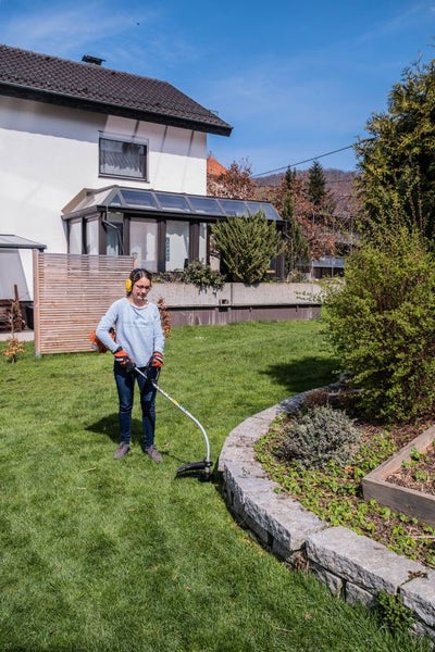 Frau arbeitet mit einem Rasentrimmer im Garten