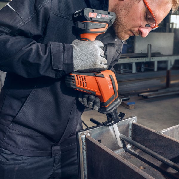 Handwerker mit Schutzbrille nutzt Fein Akku Säbelsäge zum Schneiden von Metallträgern in einer Werkstatt