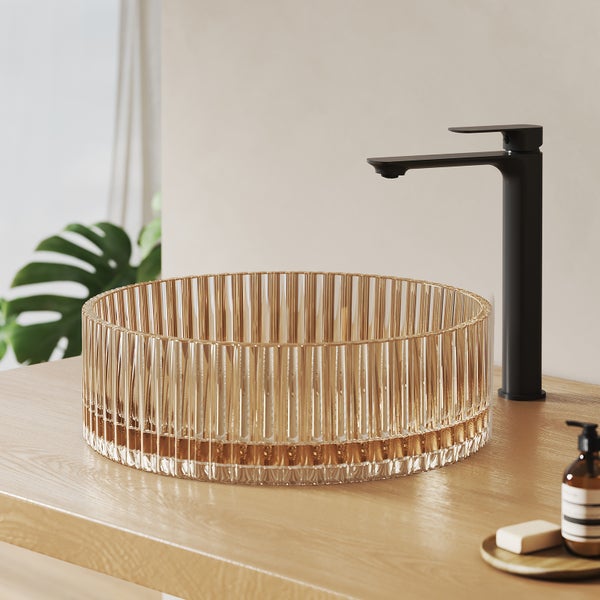 Waschbecken aus Glas mit Armatur auf einem Holztisch