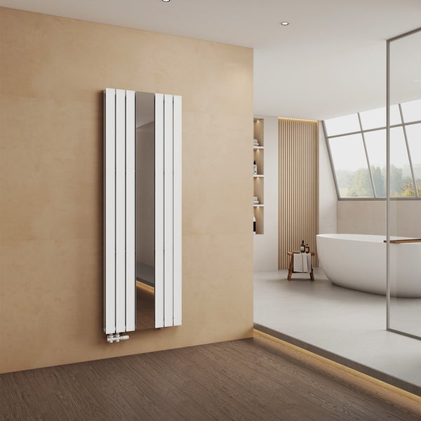 Vertikaler Designheizkörper mit Spiegel in einem hellen, modernen Badezimmer mit freistehender Badewanne und großem Fenster.