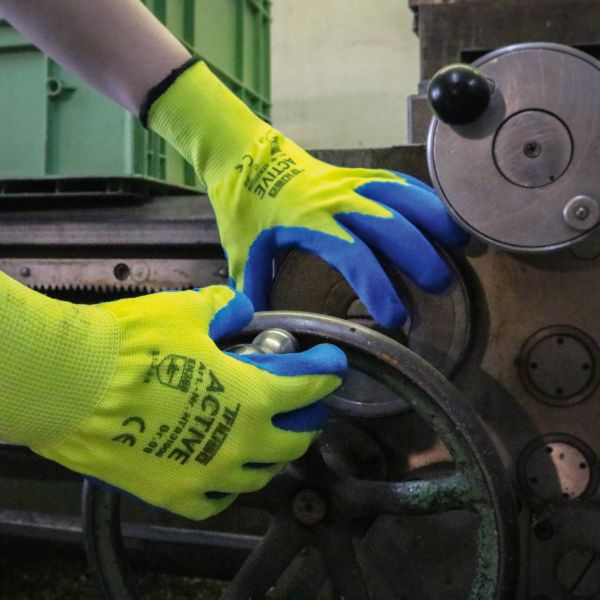 Hände mit Strickhandschuhen bedienen eine Maschine
