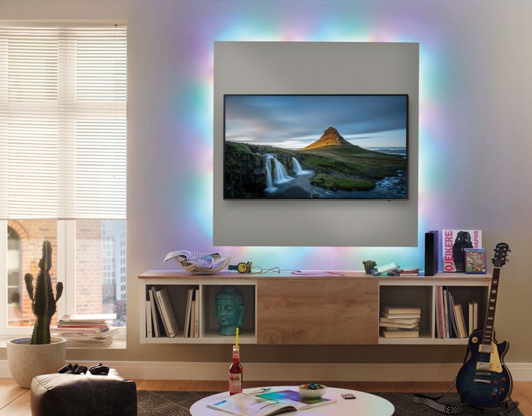 Wohnzimmer mit Fernseher, beleuchteter Wand und modernen Möbeln