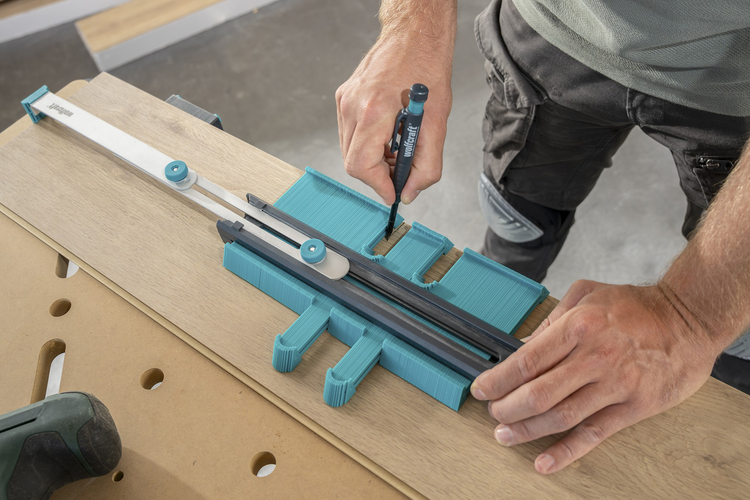 Eine Person nutzt die wolfcraft Konturenlehre und Markierhilfe um die Konturen eines Hindernisses präzise auf eine Laminatdiele zu übertragen.
