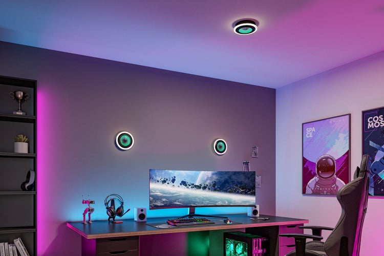 Gamingzimmer mit Schreibtisch, Monitor und Stuhl. Runde Wand- und Deckenleuchten sorgen für atmosphärische Beleuchtung in modernem Design.