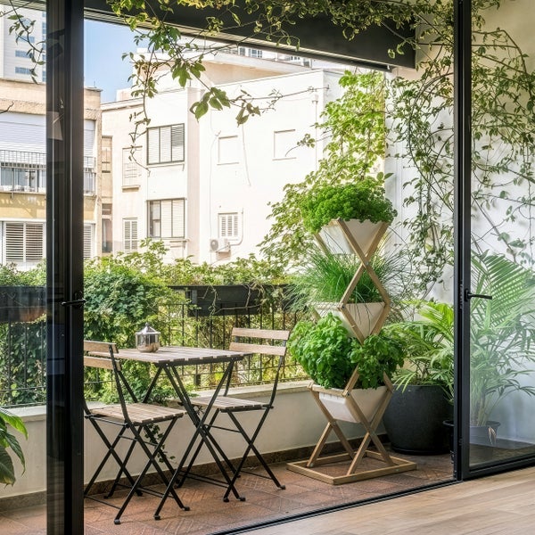 Klappbares Balkonset aus Holz auf hellem Balkon mit vertikalem Kräutergarten aus Holz und weißen Töpfen sowie grünen Pflanzen.