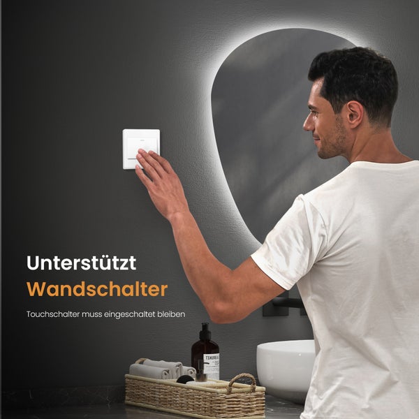 Ein Mann bedient einen Wandschalter in einem Badezimmer mit einem beleuchteten Spiegel
