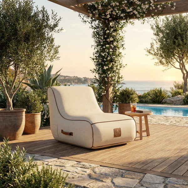 Beiger Lounge-Sessel für den Außenbereich auf einer Holzterrasse neben einem Pool mit Blick auf das Meer.
