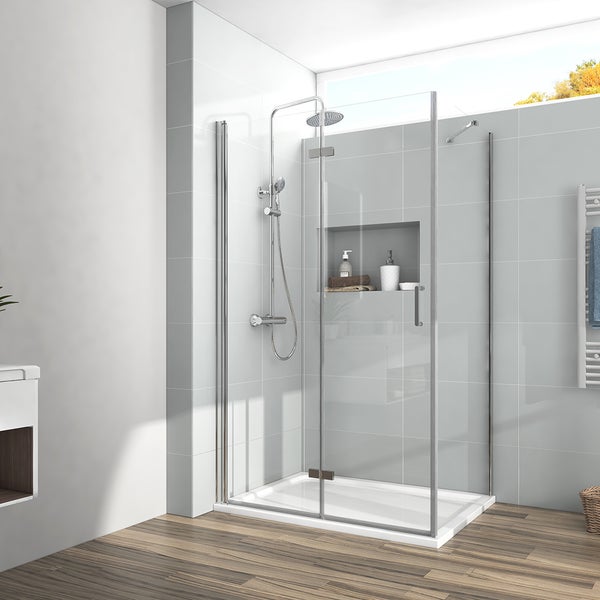Moderne Glasdusche mit einer Drehtür und Seitenwand auf einer weißen Duschwanne. Mit einem Regenduschsystem in Chrom und einer Wandnische.
