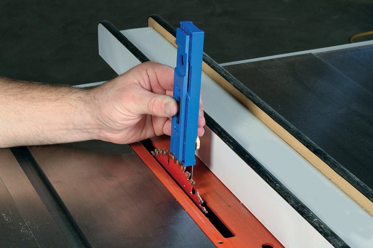 Eine Hand hält einen Gehrungseinstellwinkel über ein Sägeblatt auf einer Werkbank.