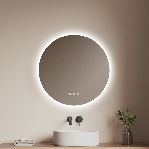 Runder LED-Badezimmerspiegel mit Hintergrundbeleuchtung über einem weißen Aufsatzwaschbecken und einer schwarzen Wandarmatur.