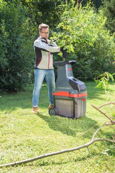 Mann bedient einen AL-KO Leisehäcksler Easy Crush LH 2810 im Garten und führt Äste mit Blättern ein.