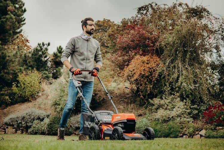 Ein Mann bedient einen Rasenmäher im Garten.