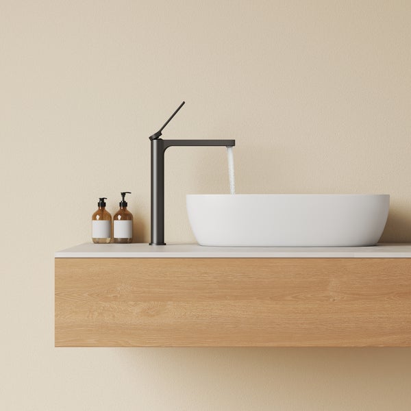 Moderne schwarze Armatur mit fließendem Wasser über einem weißen Aufsatzwaschbecken auf einem hölzernen Unterschrank.