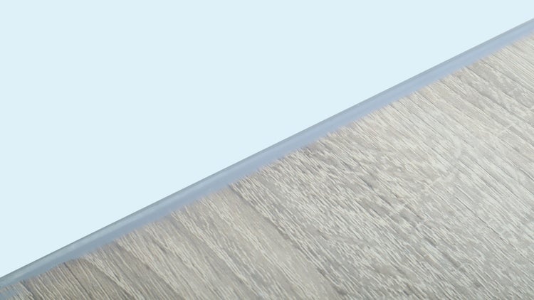 Übergangsprofil aus Metall auf einem Bodenbelag mit Holzstruktur.