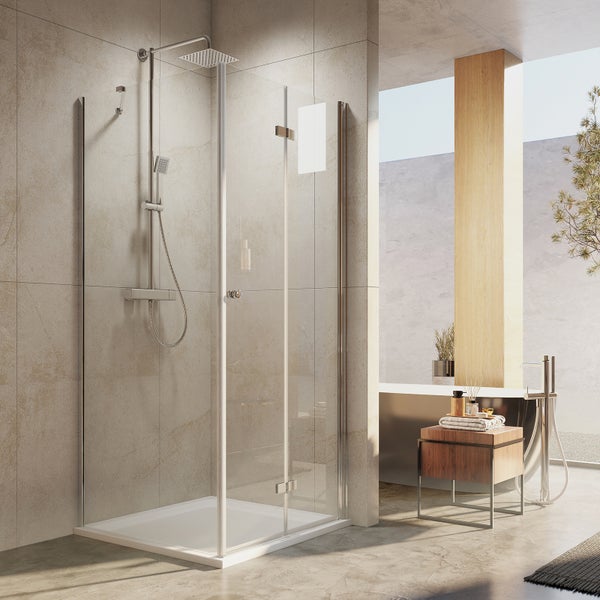Moderne Eckduschkabine mit Glaswänden, Regenduschkopf und Handbrause in einem hell gefliesten Badezimmer mit Badewanne.