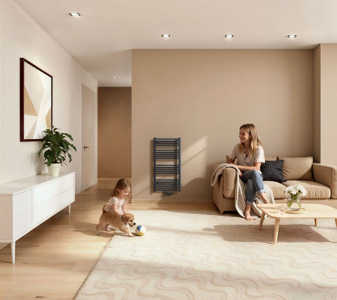 Wohnzimmer mit Heizkörper, Sofa, Couchtisch und spielenden Kindern mit Hund