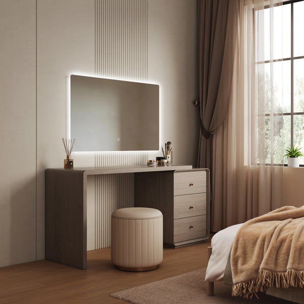Moderner Schminktisch aus Holz mit beleuchtetem Spiegel und passendem Hocker in einem elegant eingerichteten Schlafzimmer mit großen Fenstern.