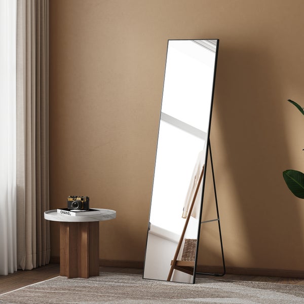 Freistehender Spiegel mit schwarzem Rahmen und Ständer, positioniert in einem Zimmer.