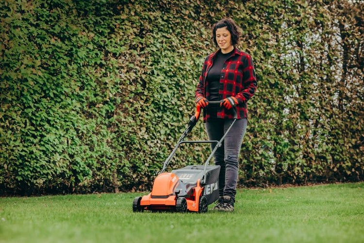 Frau benutzt einen Rasenmäher auf einem Rasen.