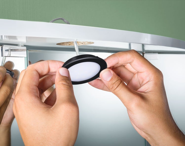 Installation einer runden Unterbauleuchte an einem Spiegelschrank