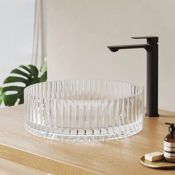 Klares Glaswaschbecken mit schwarzer Armatur auf einem Waschtisch