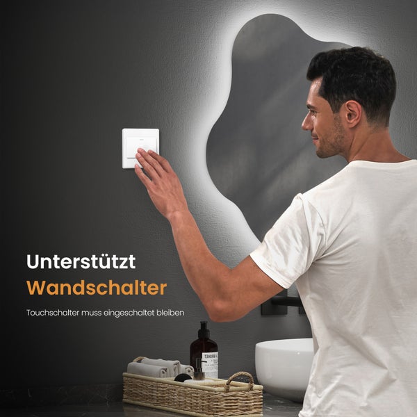 Badezimmer mit beleuchtetem Spiegel und Mann, der einen Wandschalter bedient