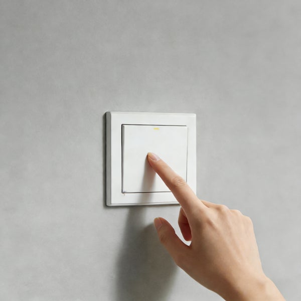 Hand betätigt einen Lichtschalter