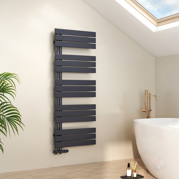 Moderner dunkelgrauer Handtuchheizkörper an einer hellen Wand in einem Badezimmer mit weißer Badewanne, goldener Armatur und Holzfußboden.